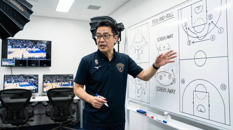 桶谷大HCが戦術ボードの前で戦術を説明する姿
