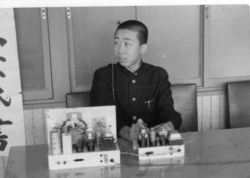 発明工夫展の入賞記念写真。詰め襟姿の加藤少年と自作の真空管アンプ装置