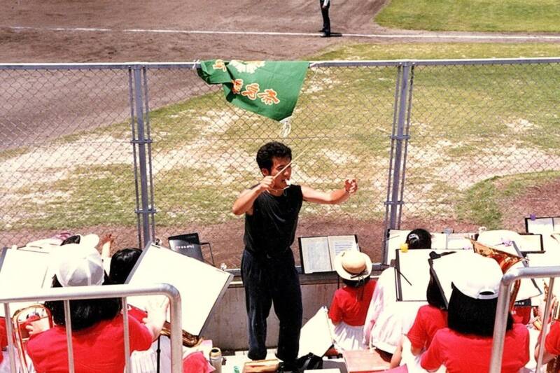 黒いTシャツ姿のOB・Yくんがアルプス席で全身でタクトを振り、吹奏楽部をリードしている。